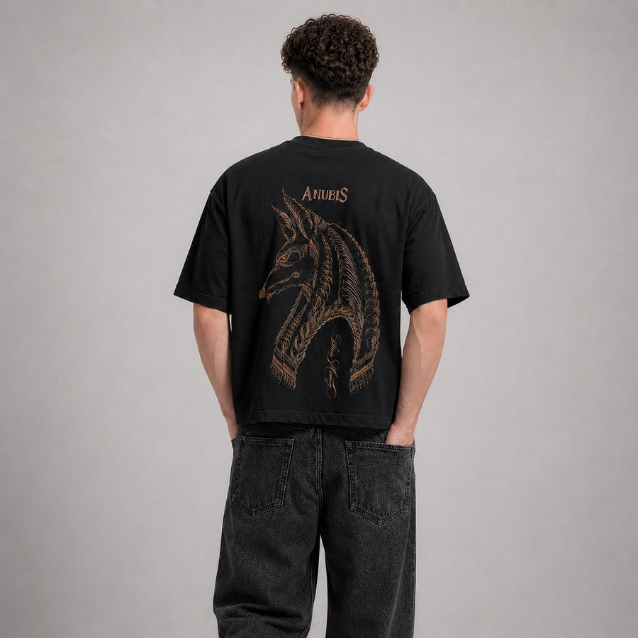 Person wearing a black t-shirt with a dragon design on the back against a gray background