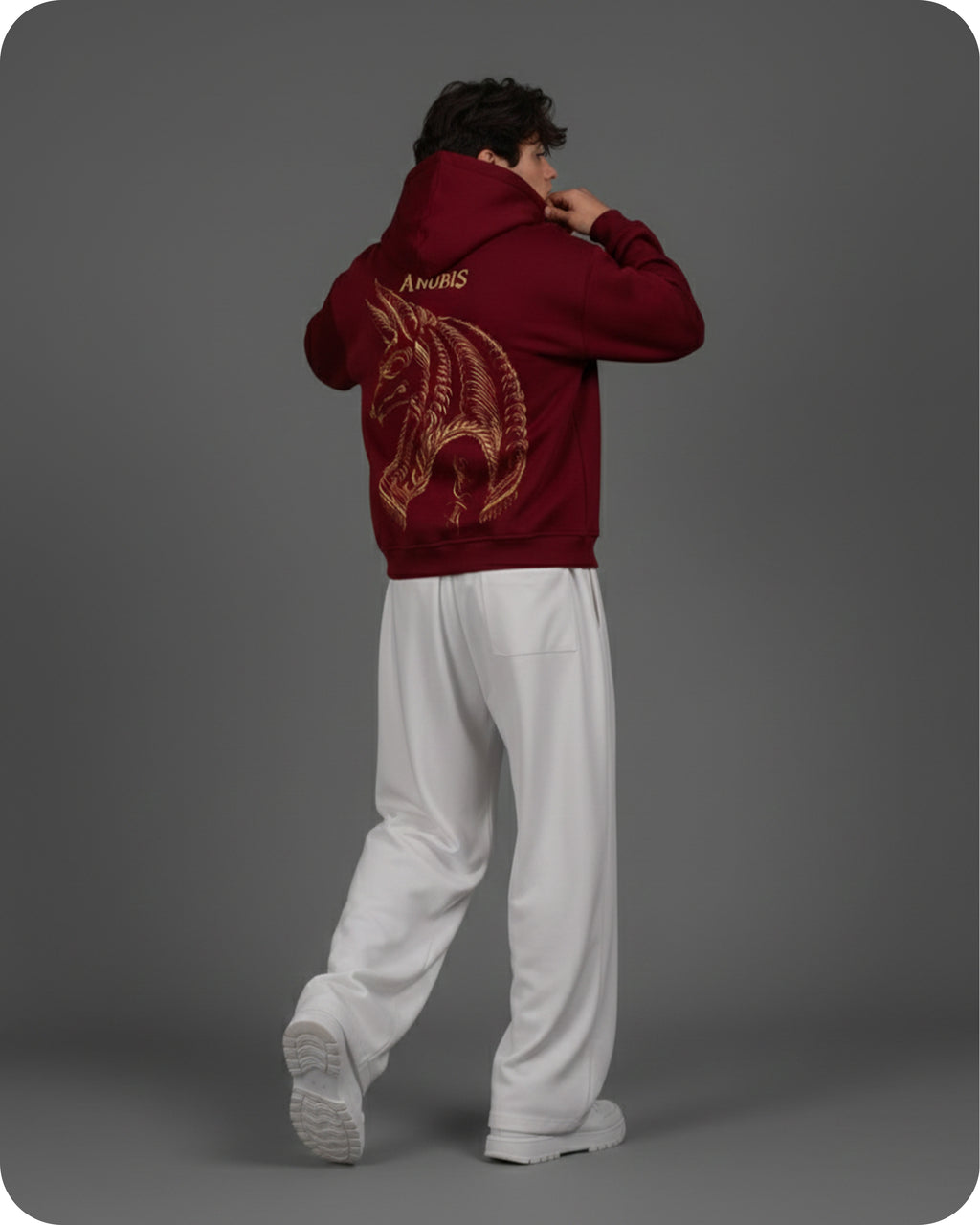 Person wearing a red hoodie with a dragon design on the back against a gray background