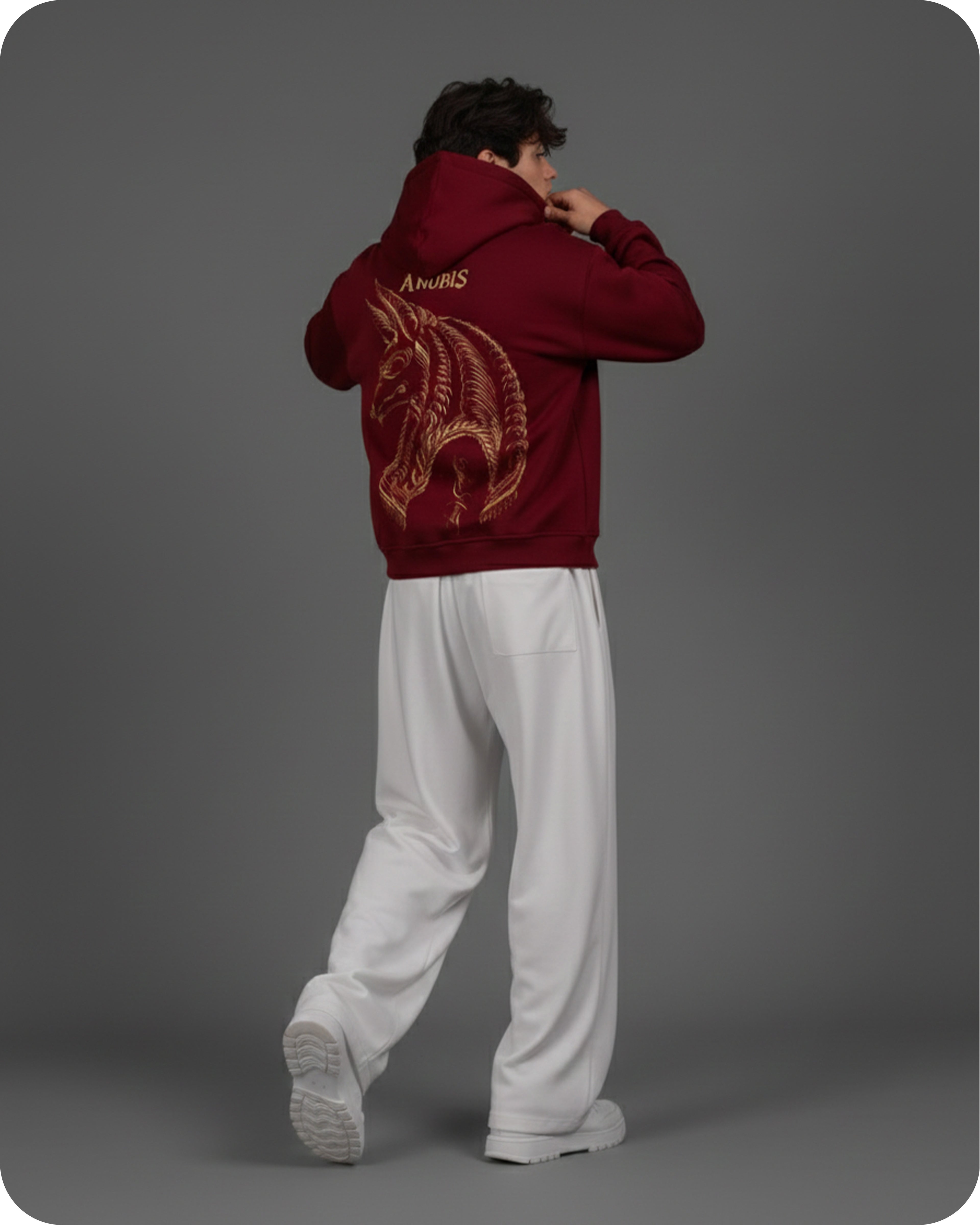 Person wearing a red hoodie with a dragon design on the back against a gray background