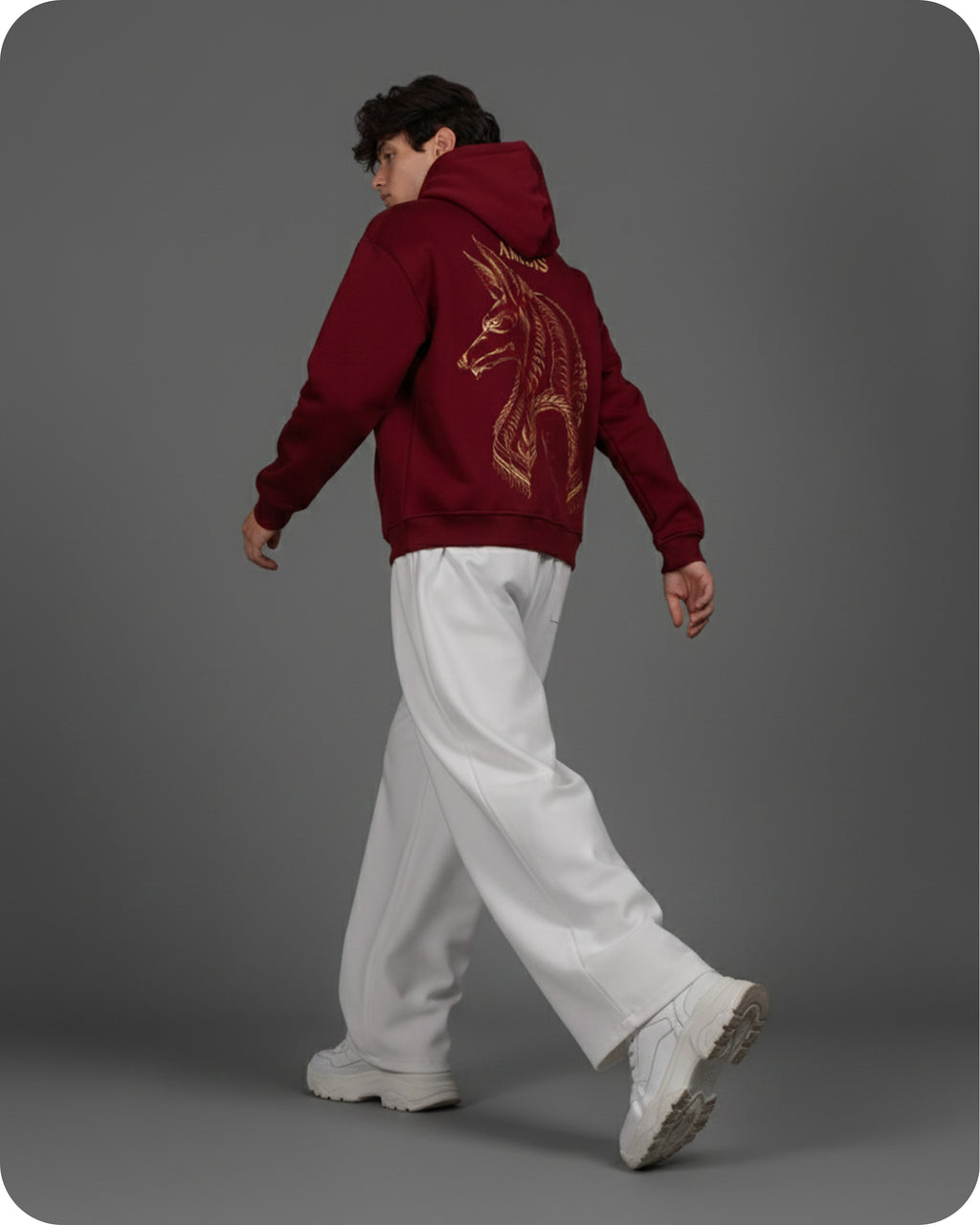 Person wearing a red hoodie with a dragon design, walking on a gray background