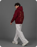Person wearing a maroon hoodie with a design on the back against a gray background