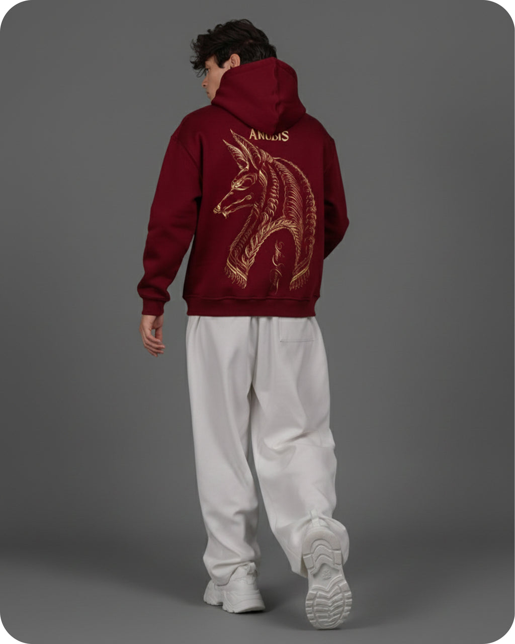 Person wearing a maroon hoodie with a dragon design on the back against a gray background