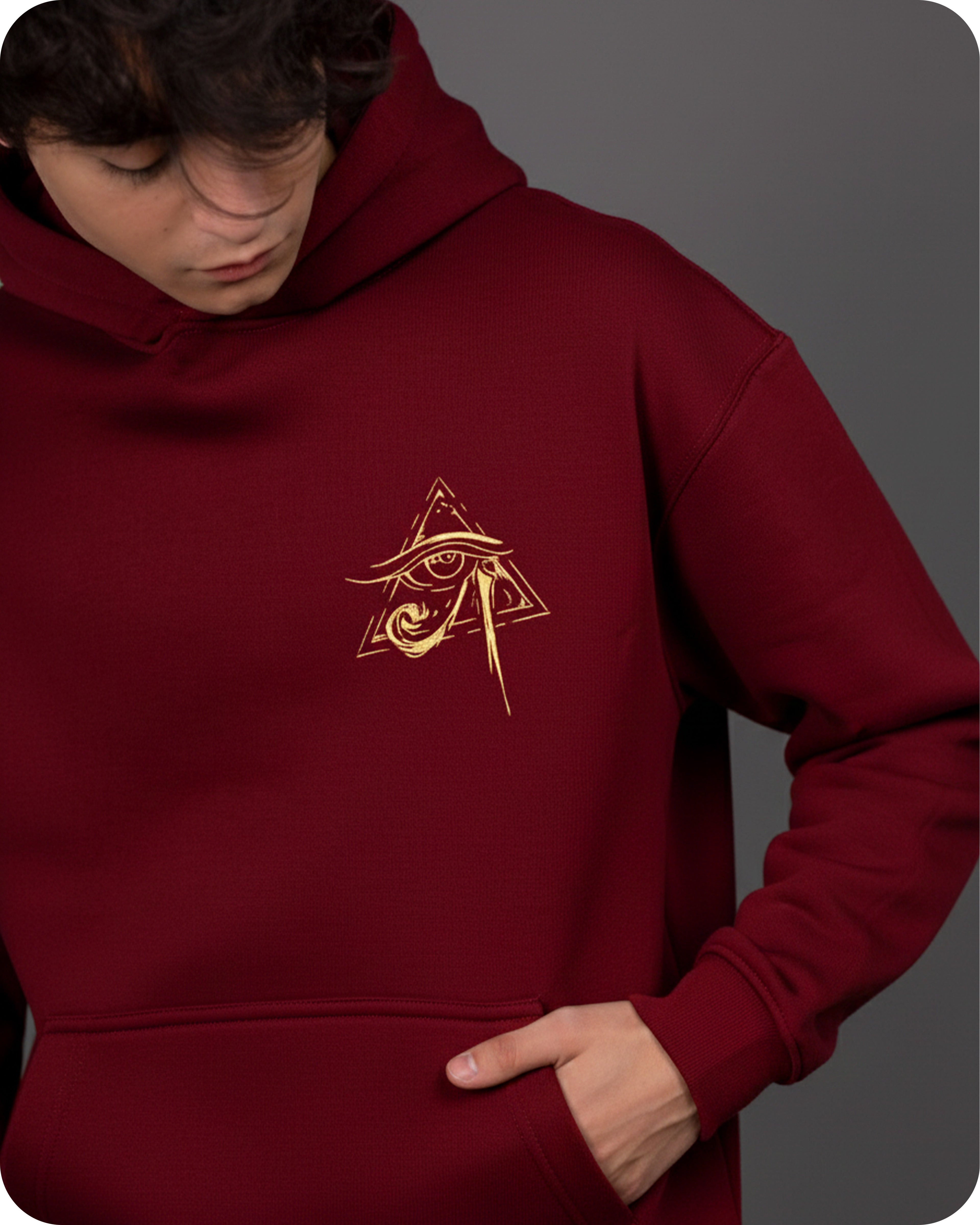 Maroon hoodie with gold emblem worn by a person on a gray background