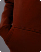 Close-up of a brown hoodie with a focus on the sleeve and fabric texture.