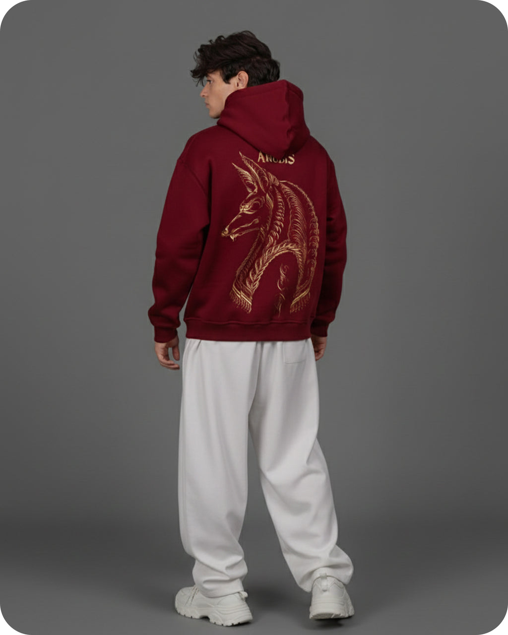 Person wearing a maroon hoodie with a dragon design on the back against a gray background