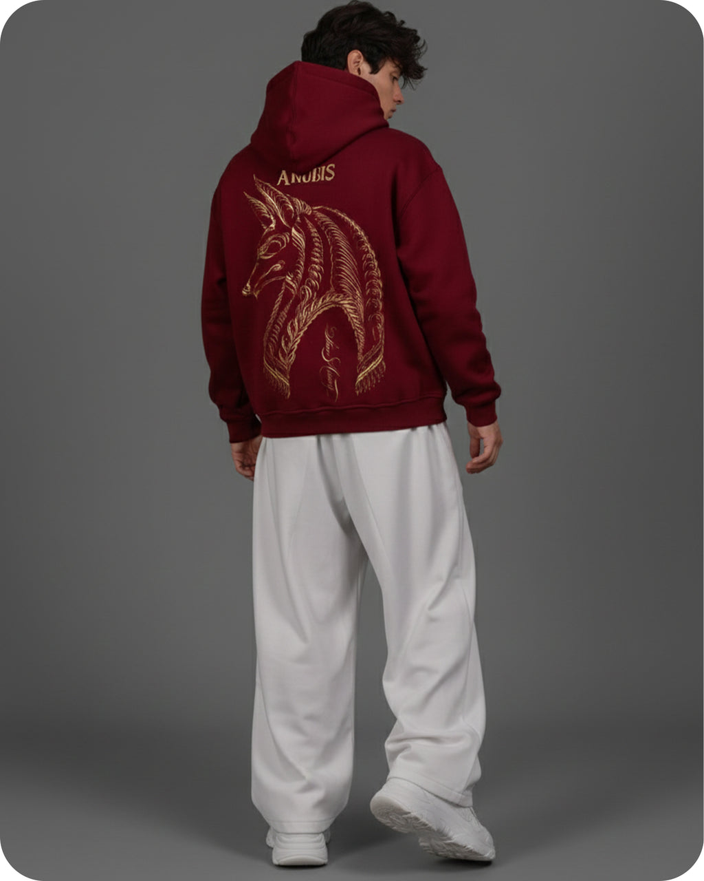Person wearing a maroon hoodie with a gold dragon design on the back, standing against a gray background.