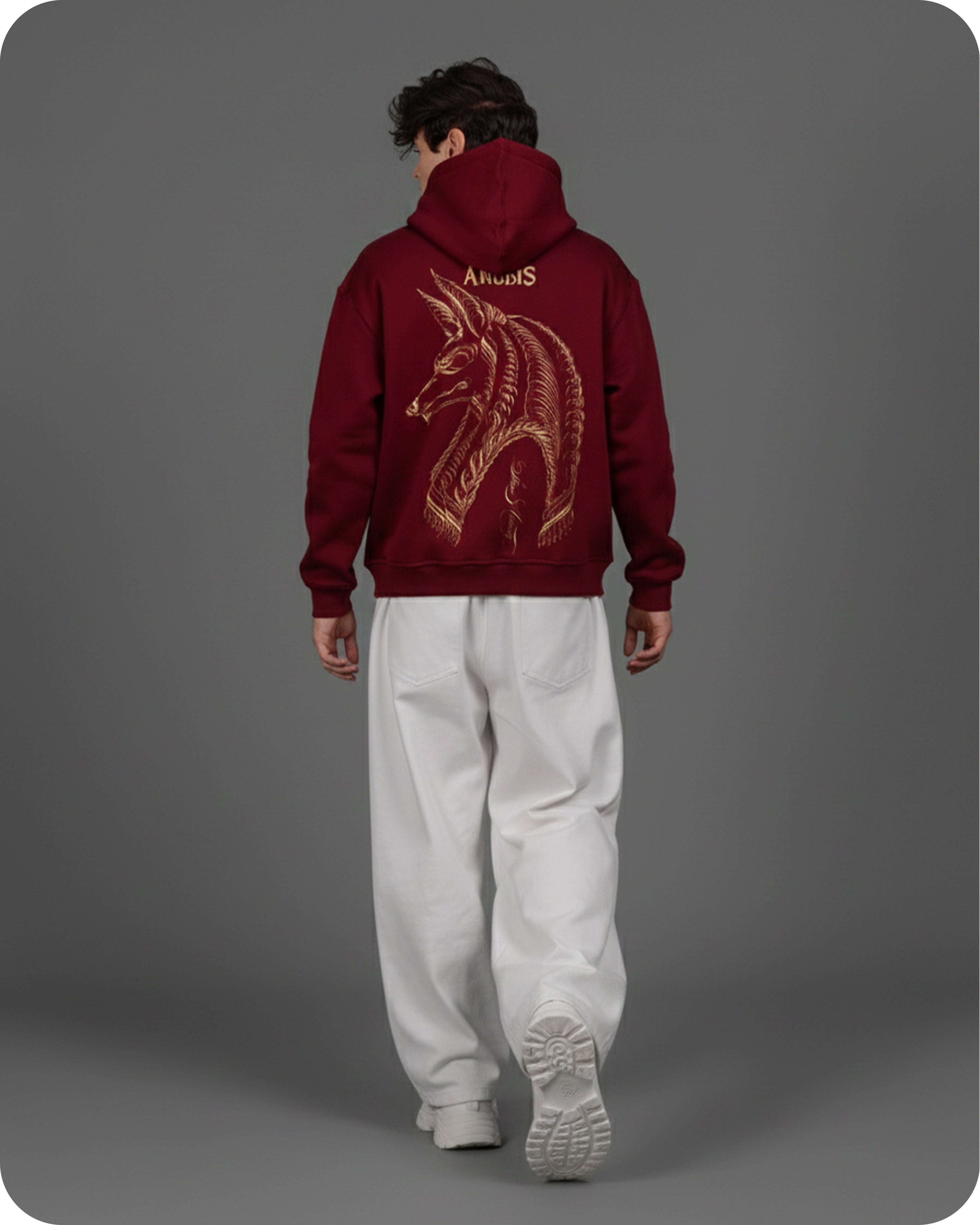 Person wearing a maroon hoodie with a gold design on the back against a gray background