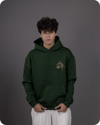 Person wearing a green hoodie with a logo on a gray background