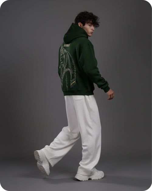 Person wearing a green hoodie with a design on the back, white pants, and white shoes against a gray background