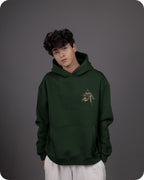 Person wearing a green hoodie with a logo on a gray background