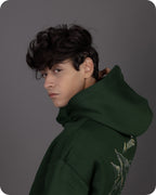 Person wearing a green hoodie with a design on the back against a gray background