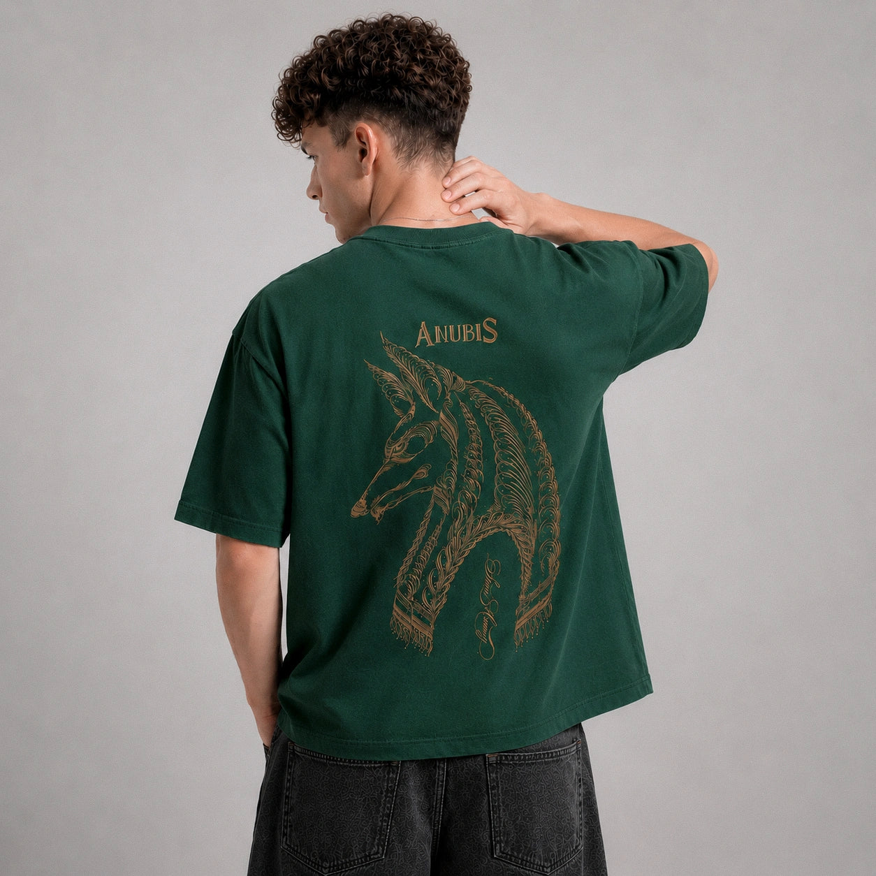 Person wearing a green t-shirt with a wolf design and 'Anubis' text on the back, against a gray background.