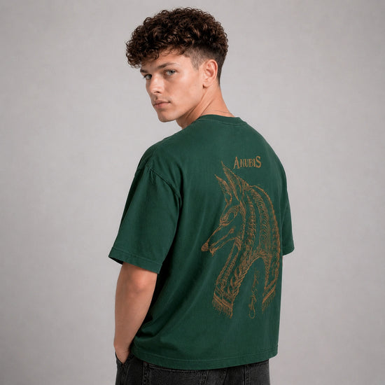 Person wearing a green t-shirt with a dragon design on the back against a gray background