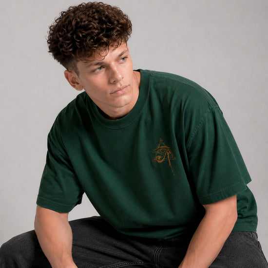 Person wearing a green t-shirt with a logo on a gray background
