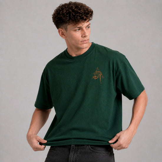 Man wearing a green t-shirt with a small logo on a gray background
