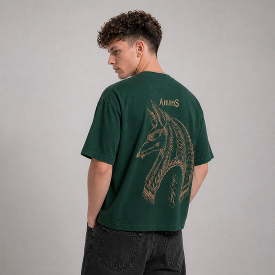 Person wearing a green t-shirt with a horse design on the back against a gray background