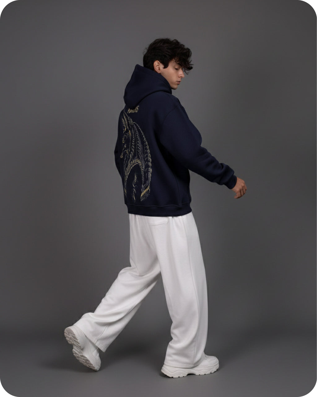 Person wearing a dark hoodie with a decorative back design on a gray background