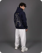 Person wearing a navy hoodie with a unicorn design on the back, standing against a gray background