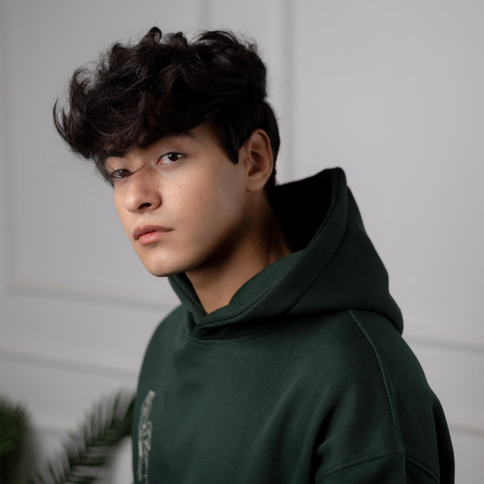 Person wearing a dark green hoodie against a neutral background