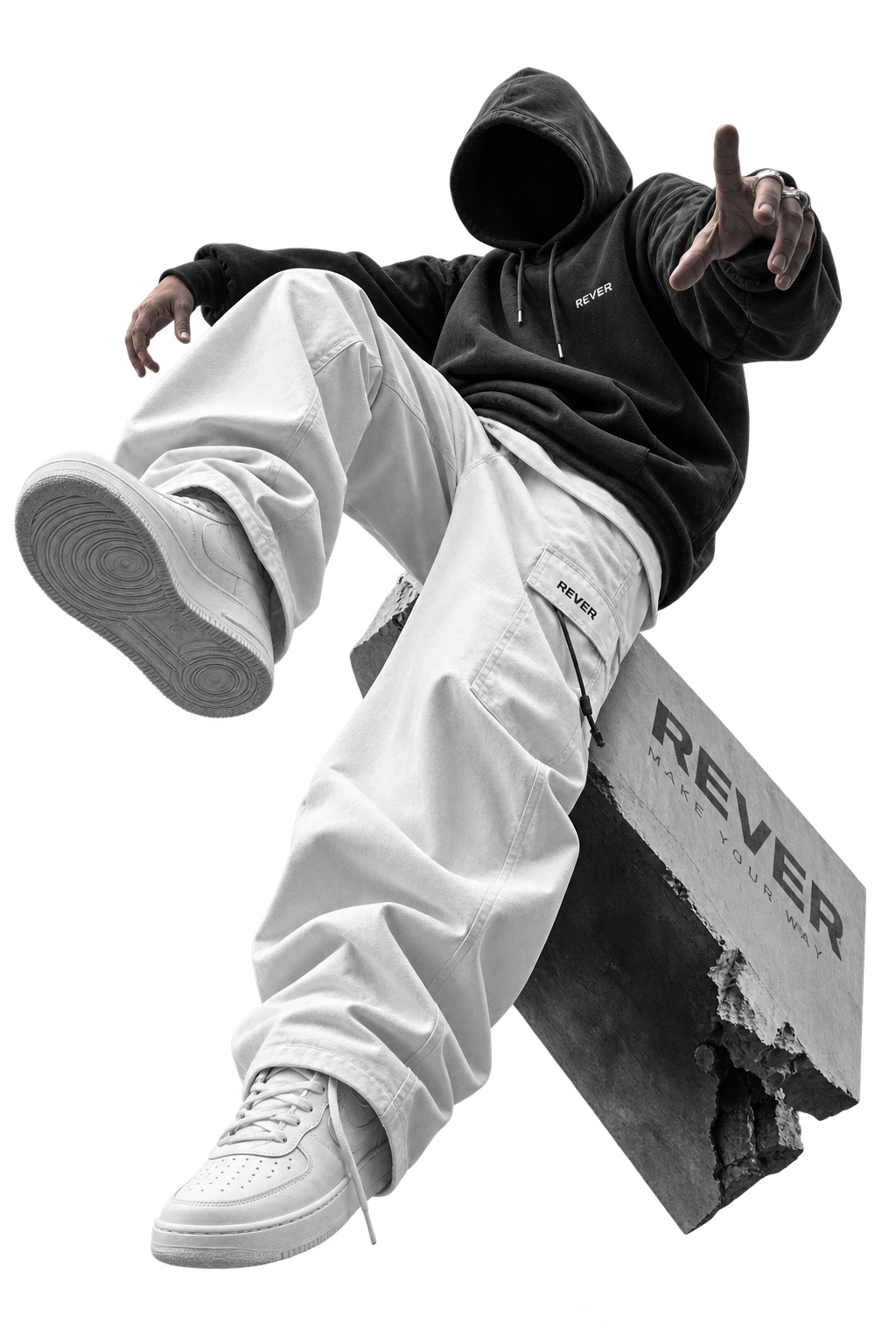 A person floating in midair wearing a black hoodie, white cargo pants, and white sneakers, surrounded by glossy metallic abstract rings and draped black fabric on a plain white background.