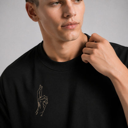 Man wearing a black t-shirt with an embroidered design on a gray background