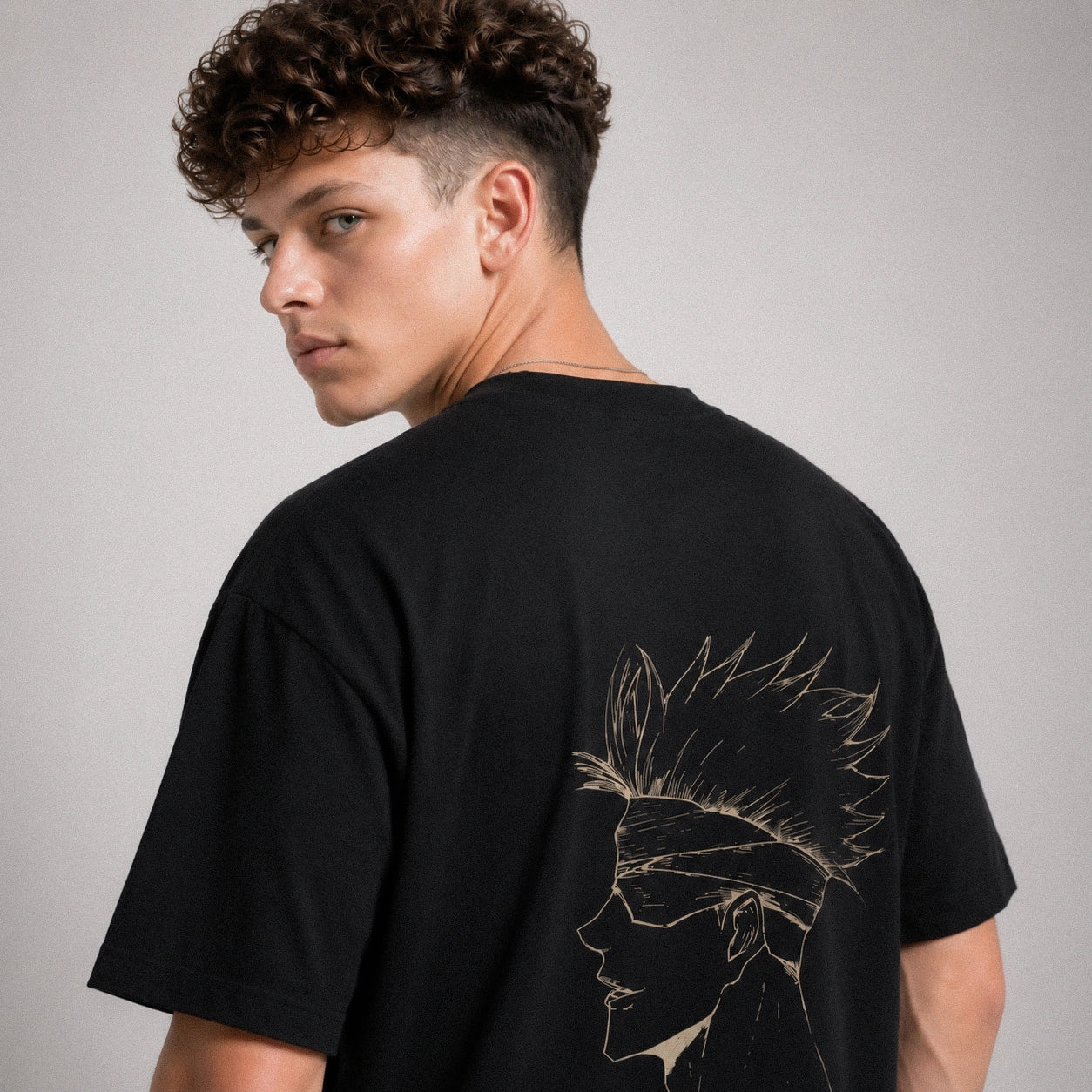 Person wearing a black t-shirt with a design on the back against a gray background