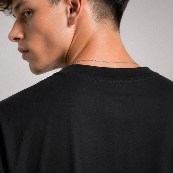 Person wearing a black shirt with a minimalistic design on a plain background