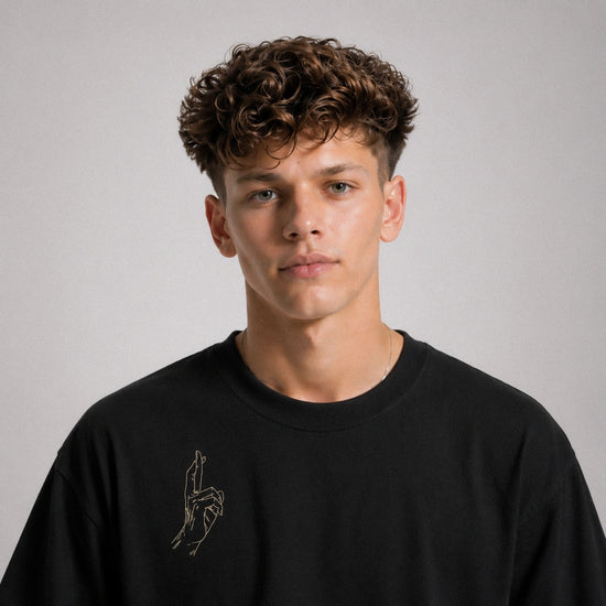 Man wearing a black sweatshirt with a small design on a plain background