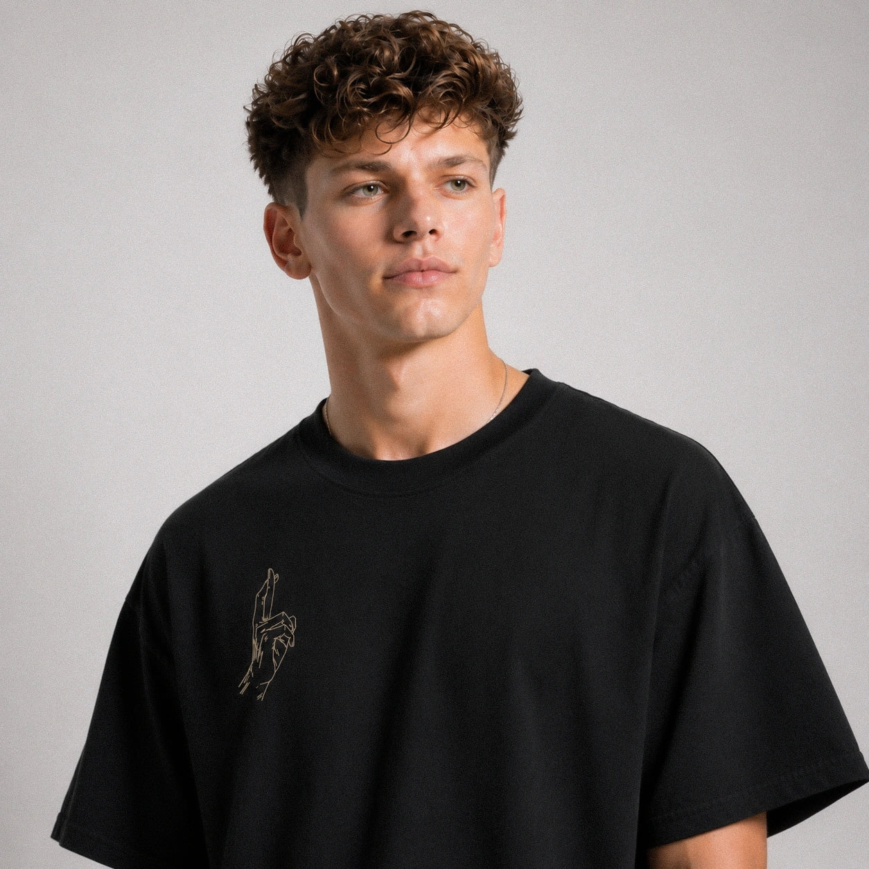 Man wearing a black t-shirt with a small design on a gray background