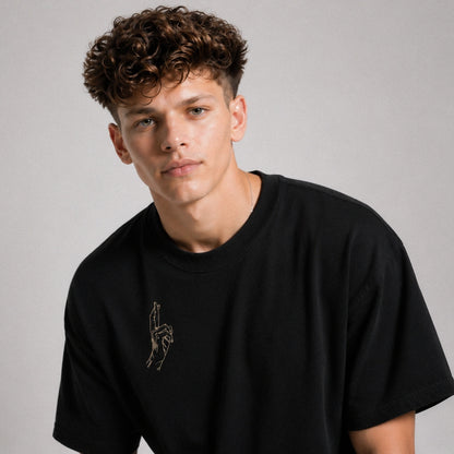 Man wearing a black t-shirt with a small graphic on a gray background
