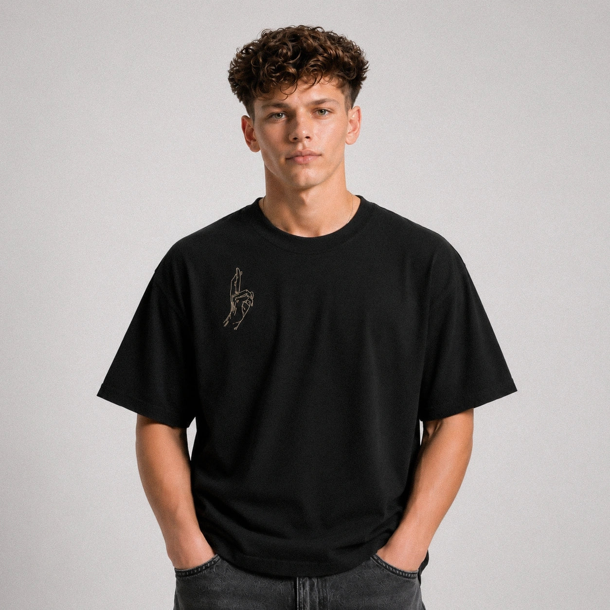 Person wearing a black t-shirt with a small design on a plain background