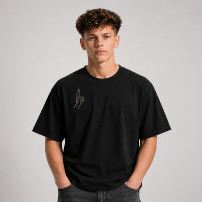 Person wearing a black t-shirt with a small design on a plain background