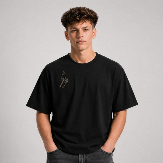 Person wearing a black t-shirt with a small design on a plain background
