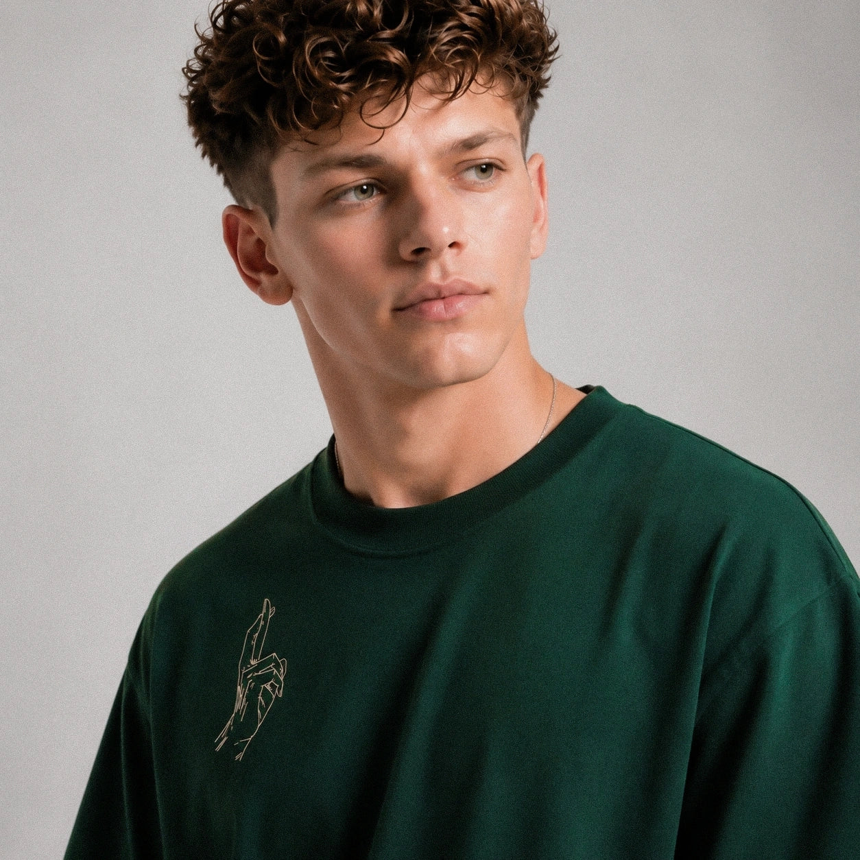 Man wearing a dark green sweatshirt with a logo on a gray background