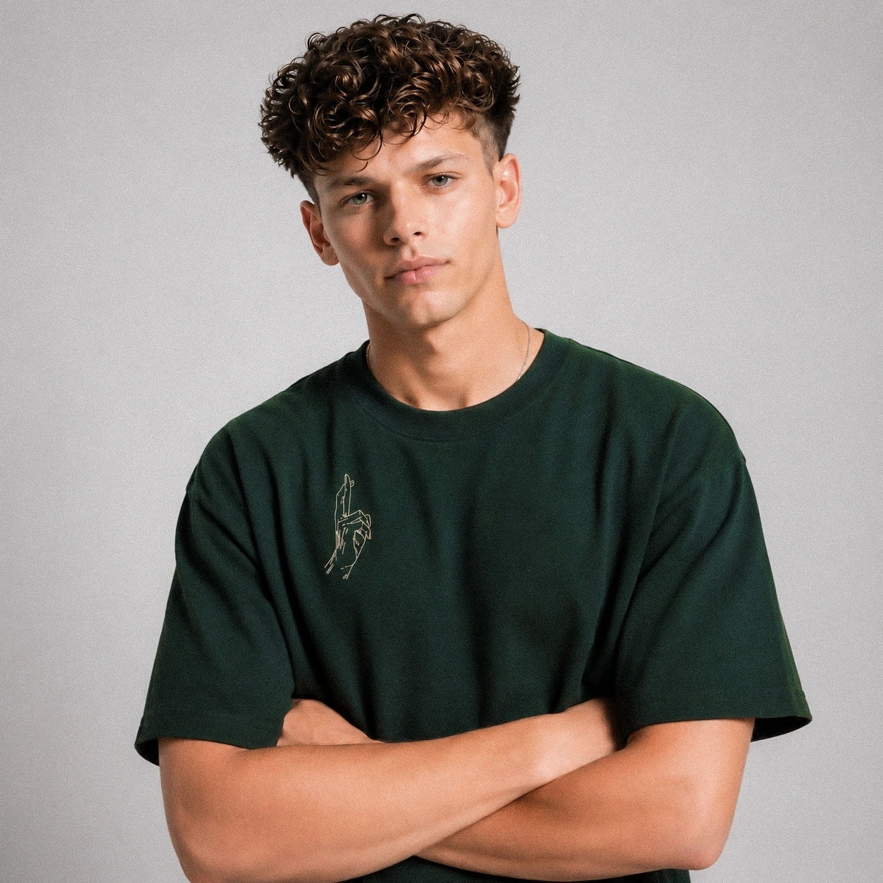 Man wearing a green t-shirt with a small graphic on a gray background