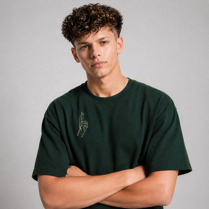 Man wearing a green t-shirt with a small graphic on a gray background