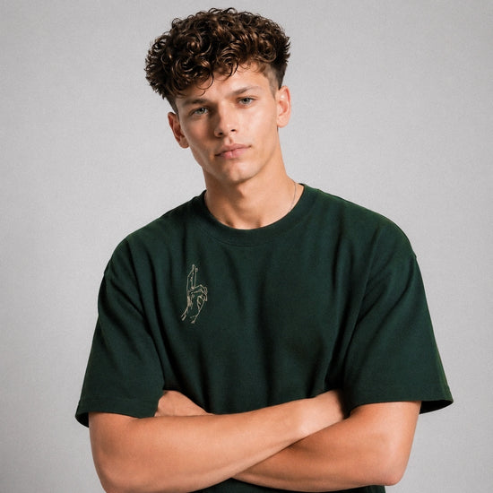 Man wearing a green t-shirt with a small graphic on a gray background