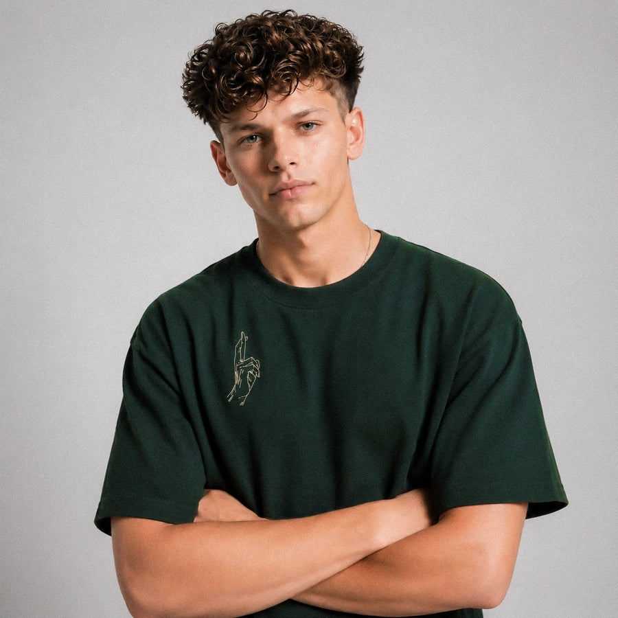 Man wearing a green t-shirt with a small graphic on a gray background