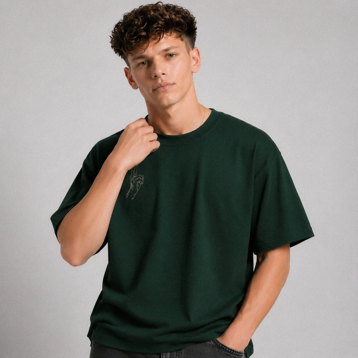 Man wearing a dark green t-shirt with a logo on a gray background