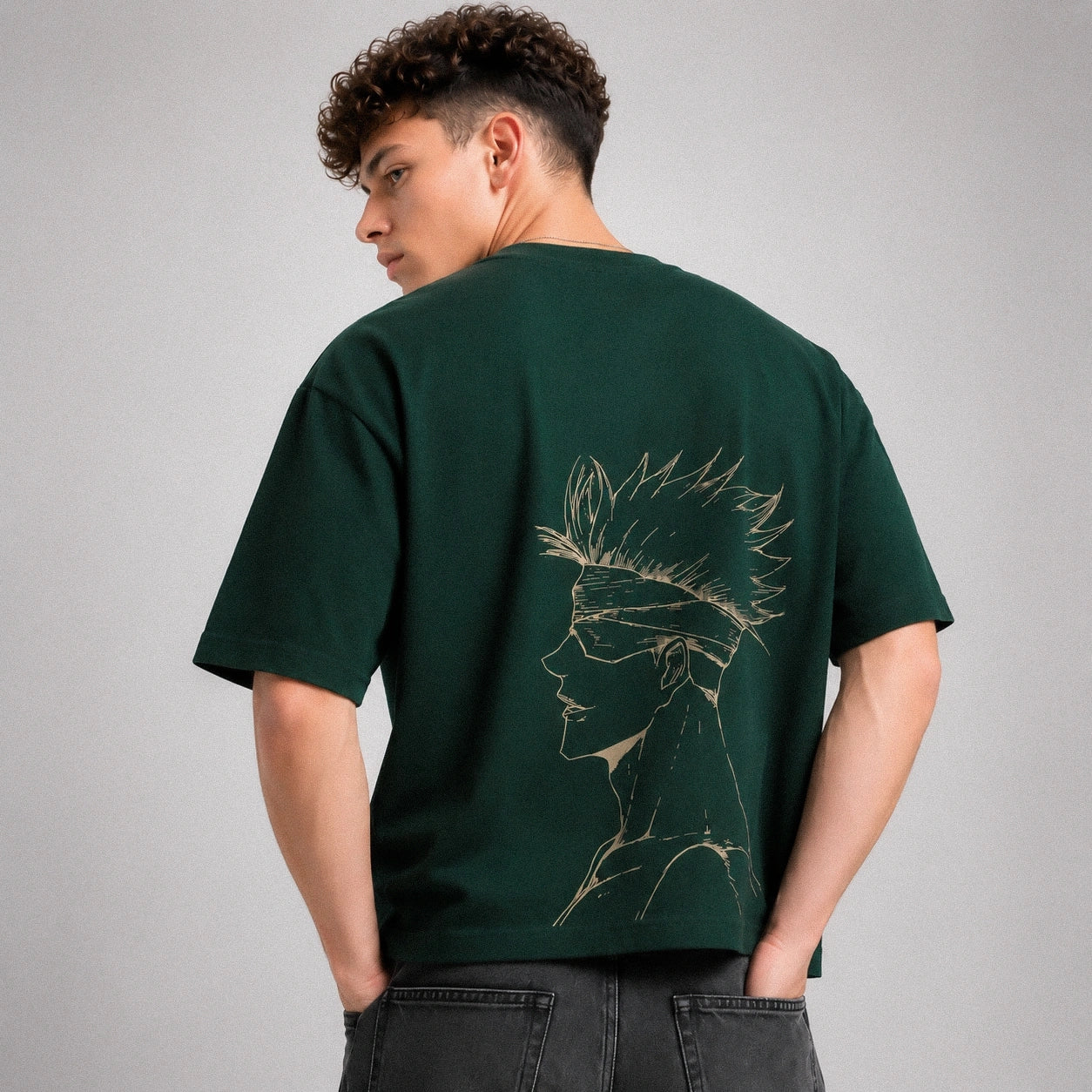 Person wearing a green t-shirt with a design on the back against a gray background