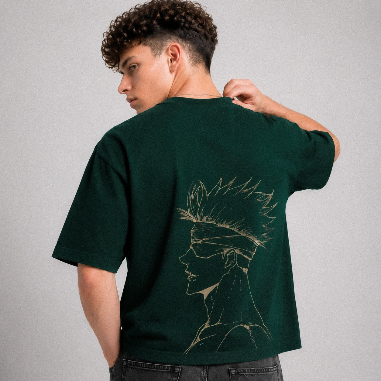 Person wearing a green t-shirt with a design on the back, standing against a gray background