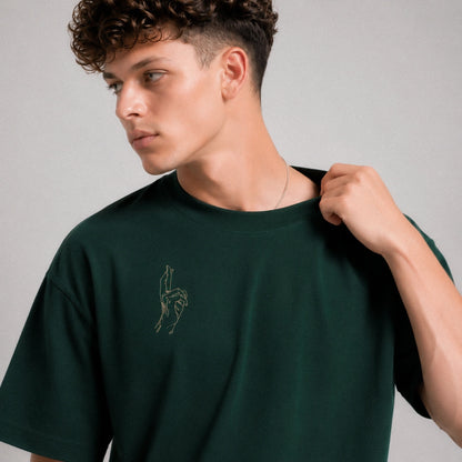 Man wearing a dark green t-shirt with a small logo on a gray background