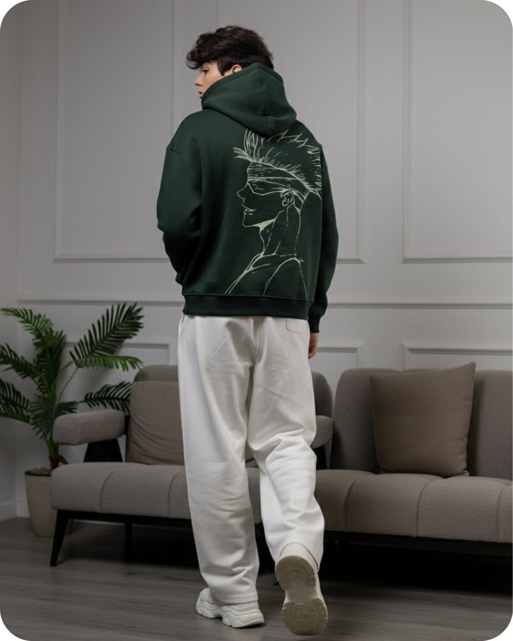 Person wearing a green hoodie with a lion design in a living room.