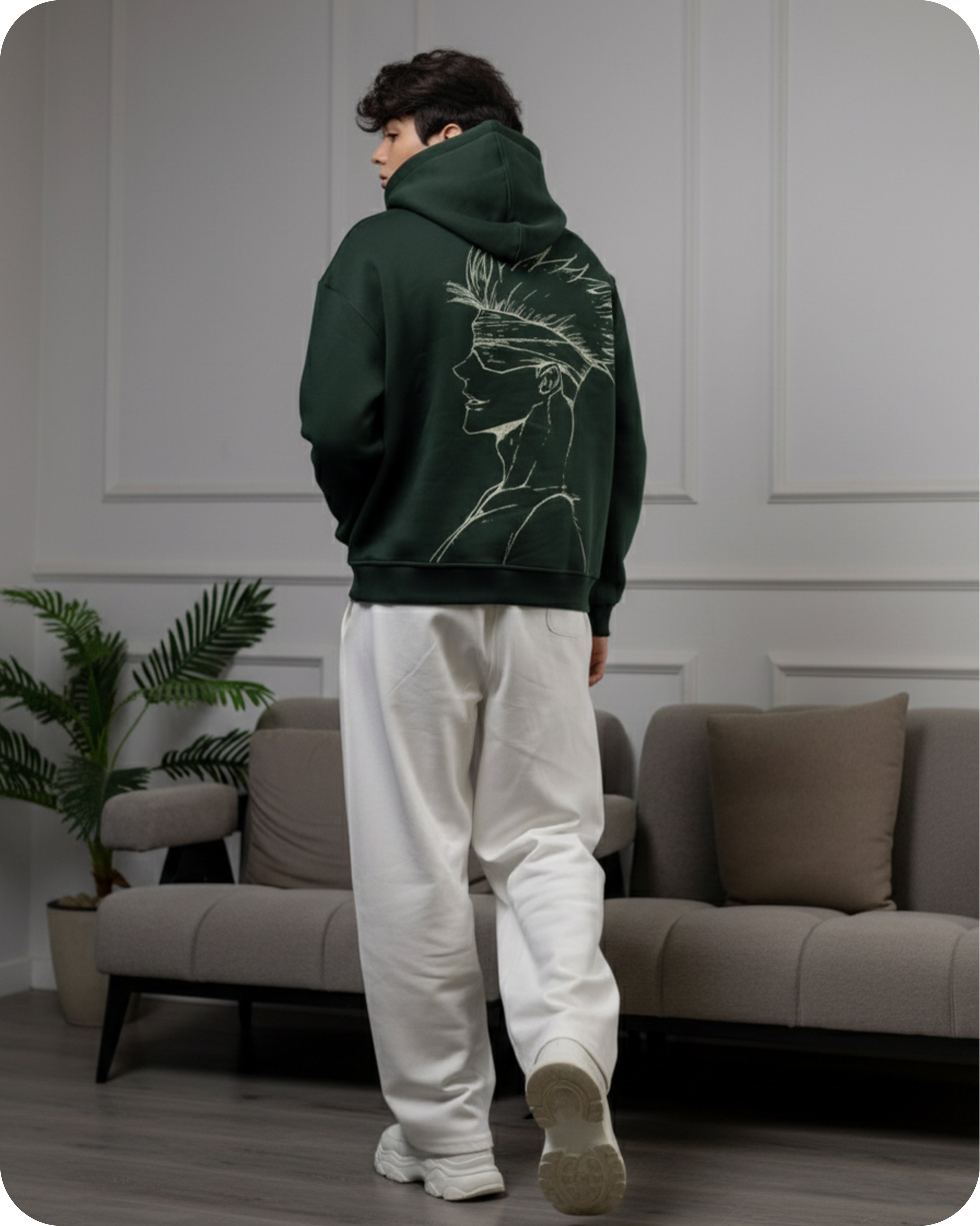 Person wearing a green hoodie with a lion design in a living room.