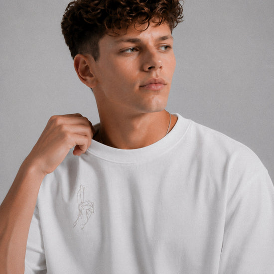 Man wearing a white t-shirt with a small design on a gray background