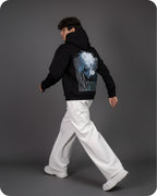 Person wearing a black hoodie with a graphic design on the back against a gray background