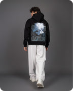 Person wearing a black hoodie with a graphic design on the back against a gray background