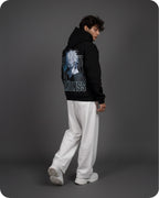 Person wearing a black hoodie with graphic design on the back against a gray background