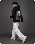 Person wearing a black hoodie with a graphic design on the back against a gray background