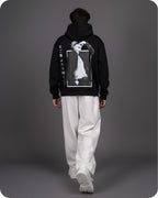 Person wearing a black hoodie with a graphic design on the back against a gray background